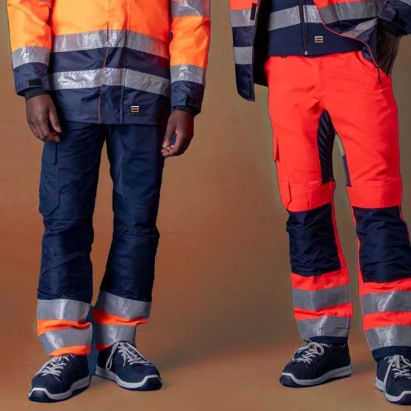 Zwei Personen tragen Warnschutzbekleidung: orange-blaue Jacken und Hosen mit reflektierenden Streifen.